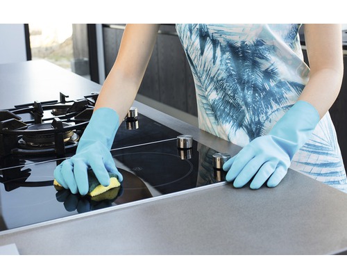 Žena čistí varnou desku houbou a rukavicemi