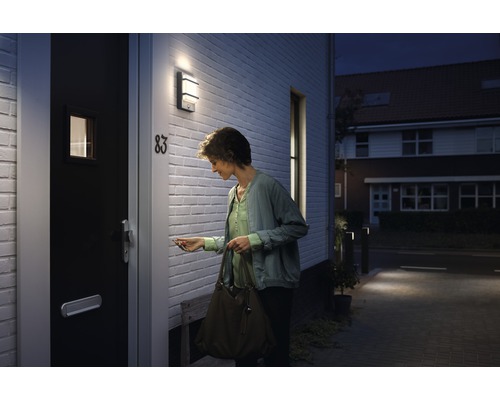 Žena odemyká vchodové dveře s venkovním světlem