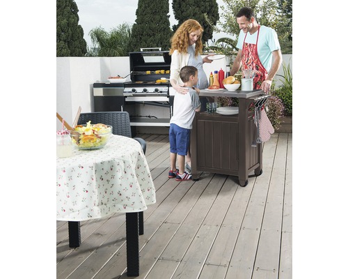 Rodina griluje venku s plynovým grilem a grilovacím vozíkem na terase.