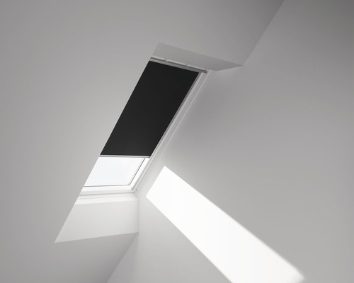 Střešní okno se zatemňovací roletou v světlé místnosti.