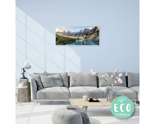 Obývací pokoj s pohovkou a nástěnnou malbou zobrazující horskou krajinu s jezerem