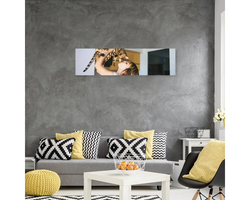 Obývací pokoj s šedou pohovkou, polštáři a nástěnnou malbou zobrazující dívku s kočkou.