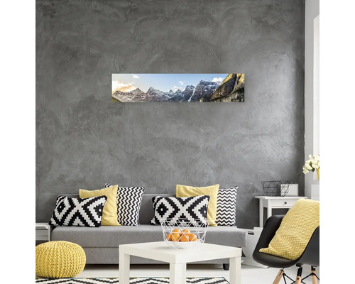 Obývací pokoj s pohovkou, polštáři, stolem a nástěnnou malbou horské krajiny.