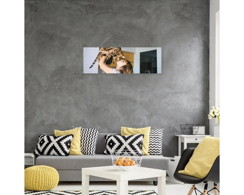 Obývací pokoj s pohovkou, polštáři, stolem a nástěnnou dekorací zobrazující ženu s kočkou.