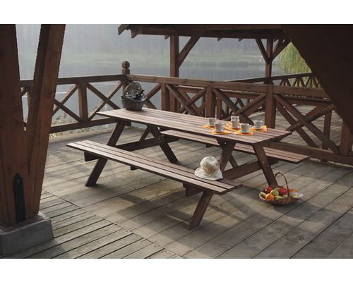Dřevěný piknikový stůl s lavicemi na terase s výhledem na jezero.