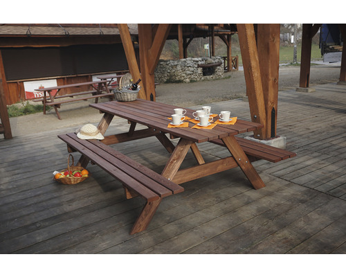 Dřevěný piknikový stůl s lavicemi pro venkovní použití, zdobený nádobím a doplňky.