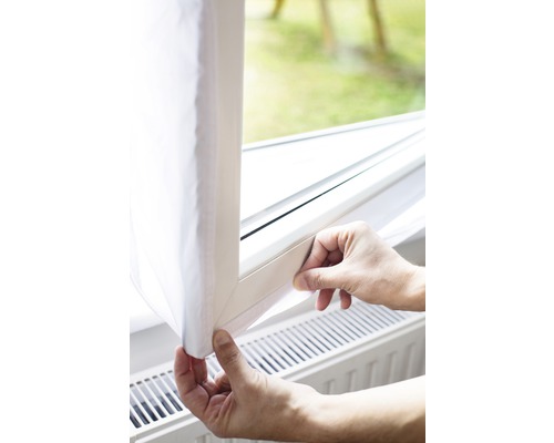 Ruce upevňují okenní těsnění na okenní rám