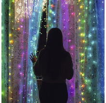 Žena stojí před oknem s světelným řetězem Twinkly