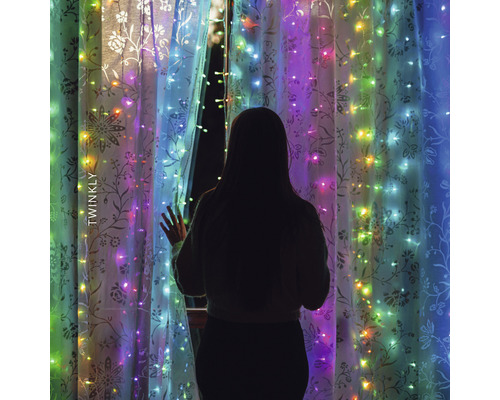 Žena stojí před oknem s světelným řetězem Twinkly