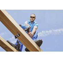 Řemeslník vrtá aku vrtačkou do dřevěného trámu