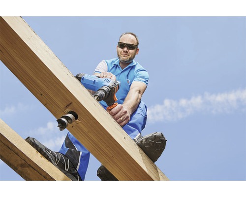 Řemeslník vrtá aku vrtačkou do dřevěného trámu