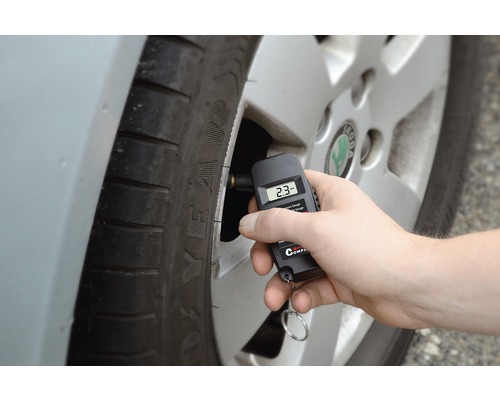 Ruka měří tlak v pneumatikách digitálním manometrem na pneumatice.