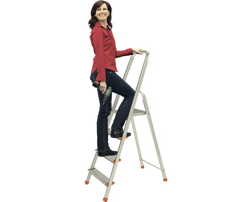Žena na hliníkovém žebříku pro domácnost se třemi schůdky a vrtačkou v ruce