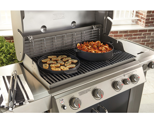 Plynový gril Weber s grilovaným jídlem a nádobím na grilovací mřížce.