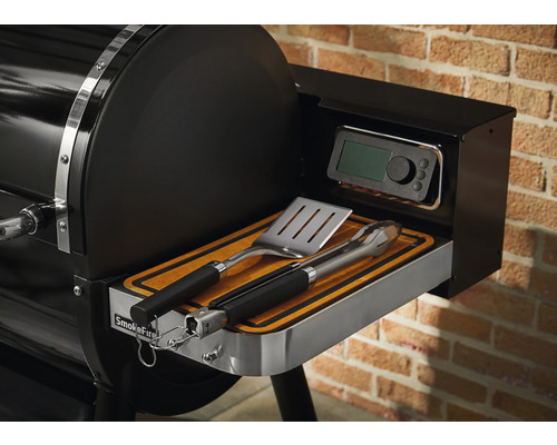 Detailní pohled na gril Weber SmokeFire s grilovacím náčiním a digitálním ovládáním.