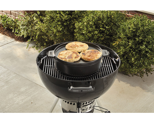 Kulatý gril s grilovací deskou a chlebem pita na zahradě