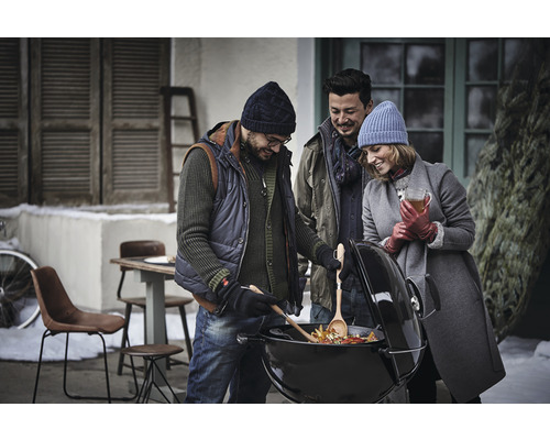 Skupina přátel griluje zeleninu v zimní zahradě na kulovém grilu.