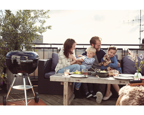 Rodina si užívá grilování s kulatým grilem na střešní terase.