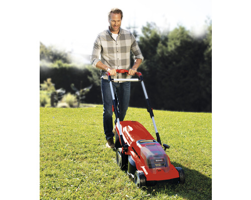 Muž obsluhuje sekačku na trávu na louce.