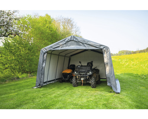 Šedá garáž na zahradní techniku s sekačkou a čtyřkolkou na zahradě