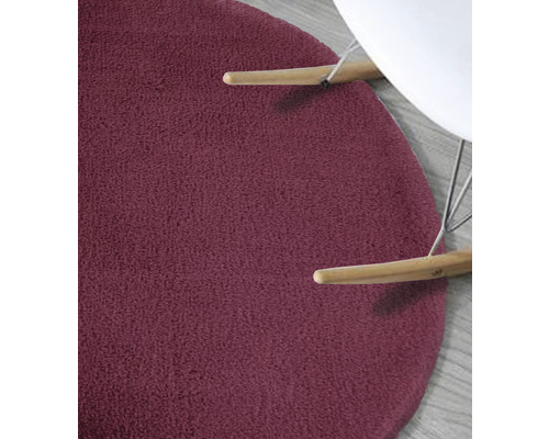 Detail kulatého, texturovaného koberce pod židlí