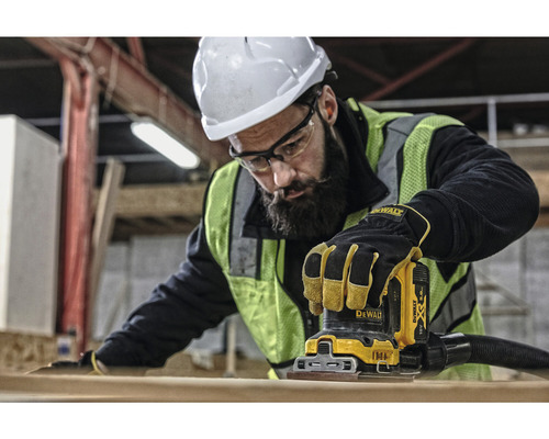 Dělník používá vibrační brusku Dewalt k broušení kusu dřeva