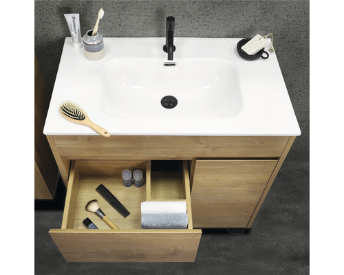 Skříňka pod umyvadlo ze dřeva s otevřenou zásuvkou a různými koupelnovými doplňky na umyvadle