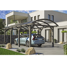 Moderní dřevěný carport s pultovou střechou a zaparkovaným autem pod ním před obytným domem.