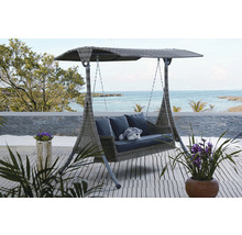 Zahradní houpačka se stříškou, polštáři a dekorací na terase s výhledem na moře