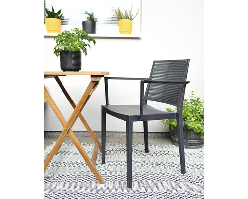 Zahradní nábytek se židlí s područkami, dřevěným stolem a kobercem na terase