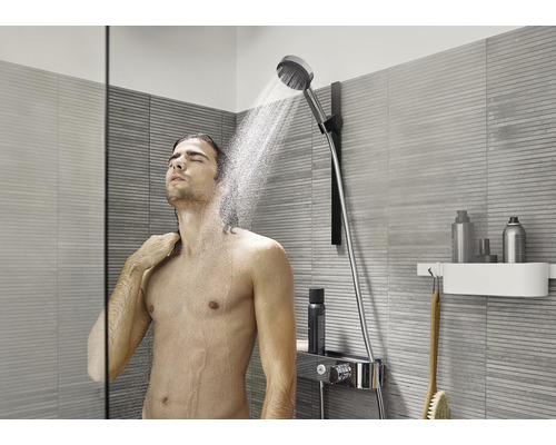 Muž pod ruční sprchou v moderní koupelně