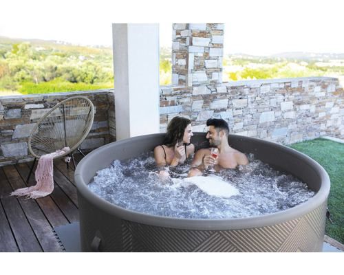 Nafukovací vířivka se dvěma lidmi na terase s kamennými prvky a židlí