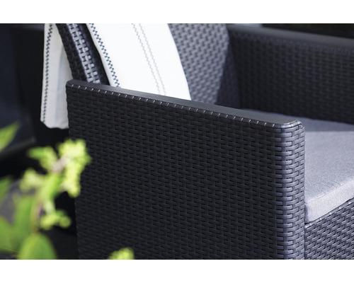 Detail černého ratanového křesla s polštářem a ručníkem