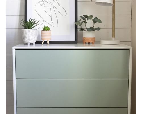 Komoda se třemi zásuvkami, rostlinami a lampou nahoře