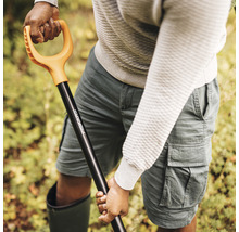 Osoba drží rýč Fiskars s rukojetí ve tvaru D.