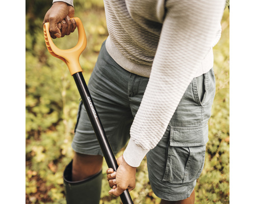 Osoba drží rýč Fiskars s rukojetí ve tvaru D.