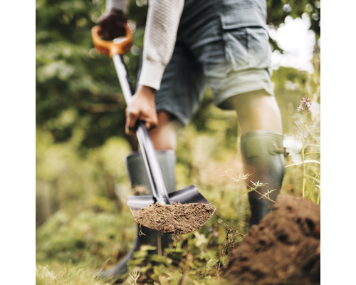Osoba kope zeminu rýčem na zahradě.