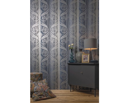 Interiér se vzorovanou tapetou, komodou, lampou, polštáři a dekorací