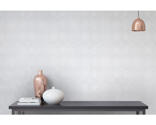 Detailní záběr na stěnu s tapetou se vzorem, zdobenou lampou, knihami a vázami na komodě