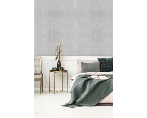 Ložnice s vzorovanou tapetou, postelí a odkládacím stolkem.