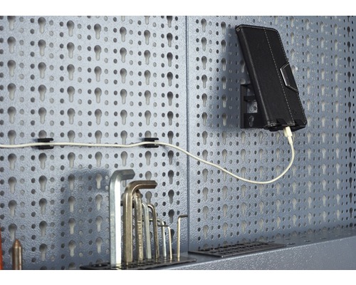 Děrovaná stěna s nářadím, tabletem a nabíjecím kabelem.