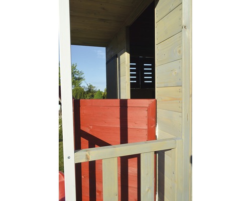 Detailní pohled na dřevěný herní domek s červenými dveřmi a dřevěným zábradlím