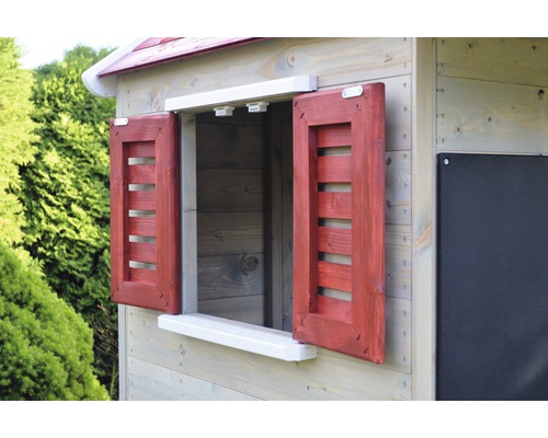 Detailní pohled na dětský domek s oknem a červenými okenicemi