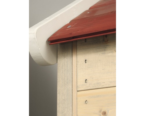 Detailní pohled na hmyzí hotel s červenou střechou a bílým přesahem střechy