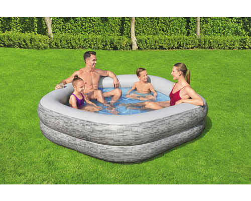 Rodina relaxuje v nafukovacím bazénu s kamenným vzhledem na zahradě