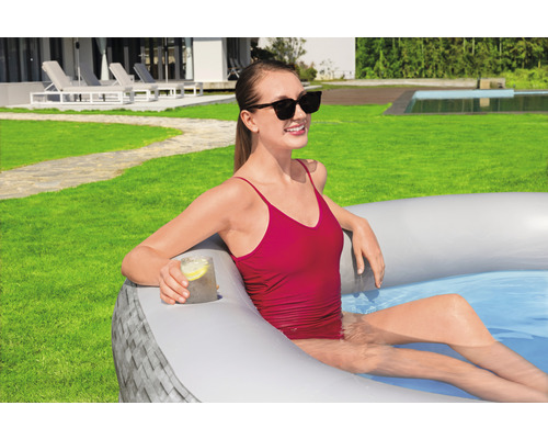 Žena relaxuje v nafukovacím bazénu na zahradě s držákem na nápoje.