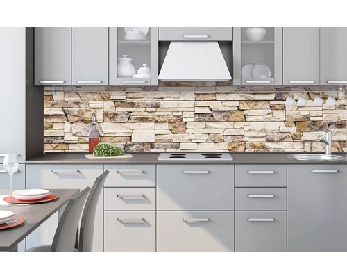 Světlá kuchyně s nástěnným panelem se vzorem kamene, dřezem, varnou deskou, digestoří a jídelním stolem.