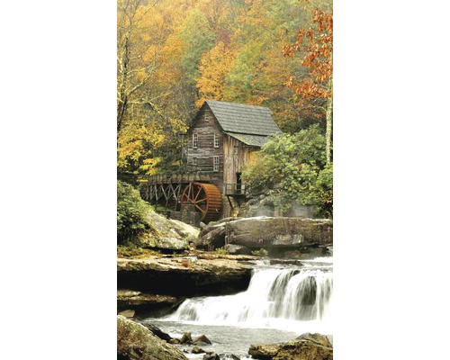 Historický mlýn u vodopádu, obklopený podzimním listím.