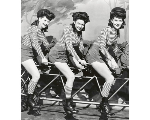 Černobílá fotografie tří žen sedících na vícemístném kole