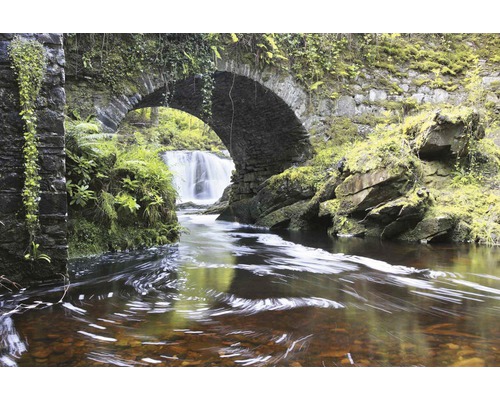 Kamenný most přes potok s vodopádem v pozadí